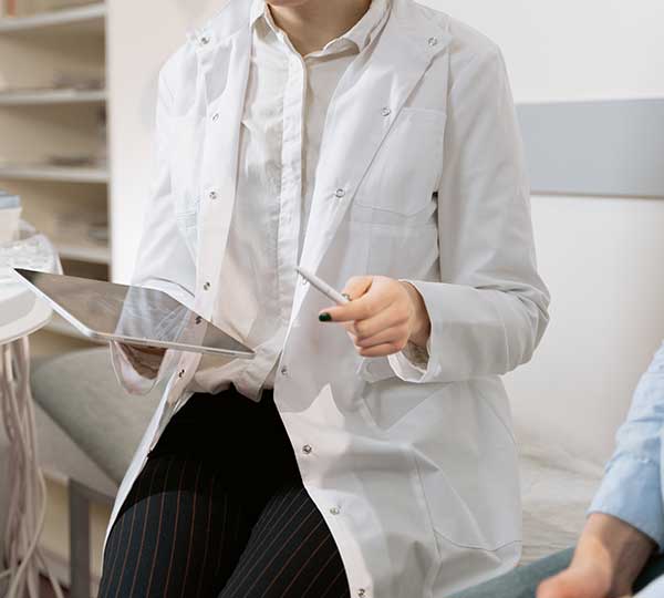 doctor wearing white coat holding a tablet and a pen